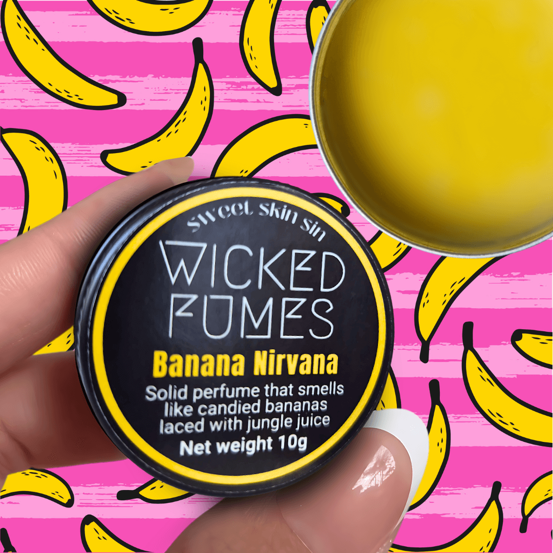 up close pic of someone holding banana nirvana solid perfume with pink and yellow wallpaper